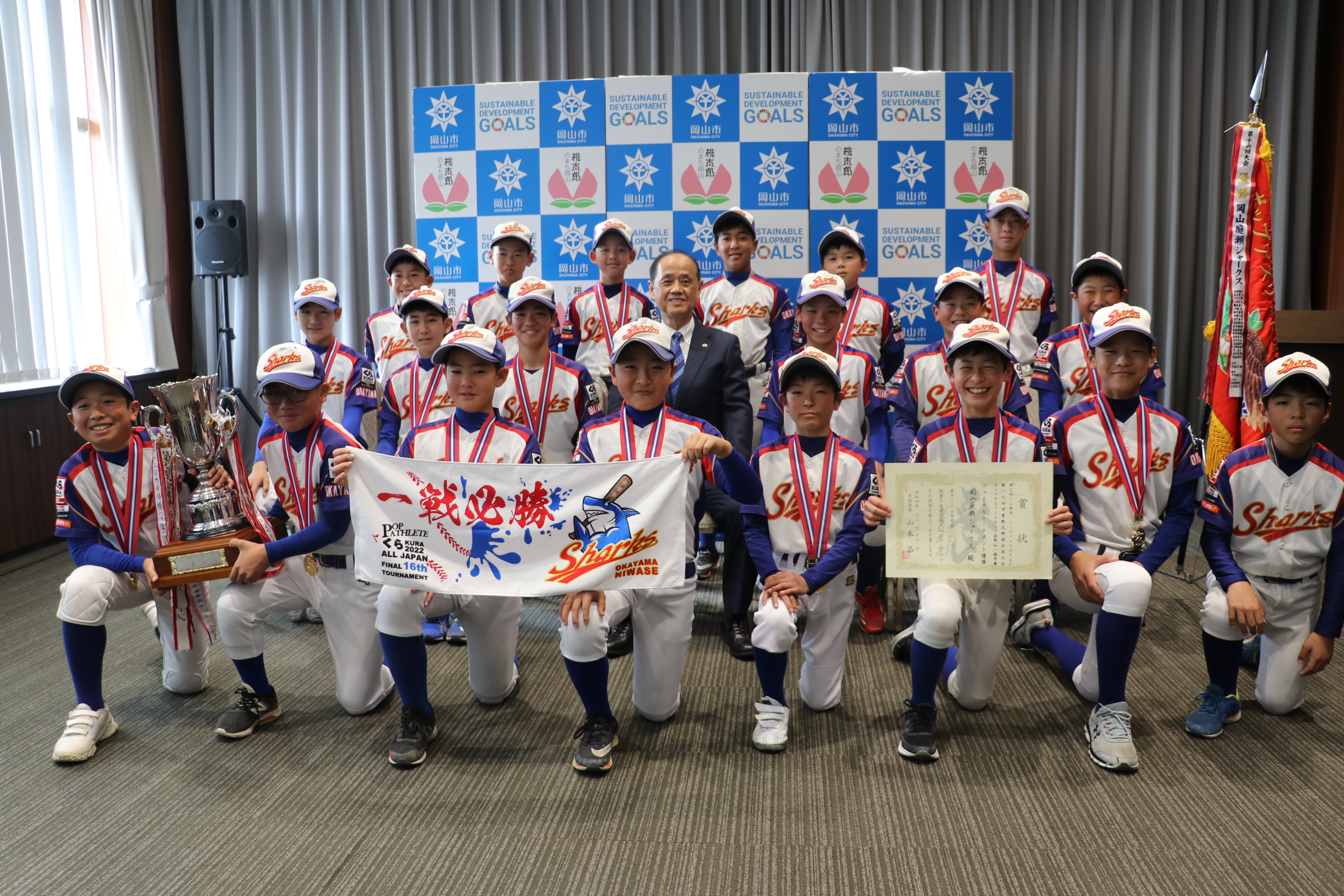 学童軟式野球の全国大会に出場する岡山庭瀬シャークスと関係者、市長、議長の集合写真