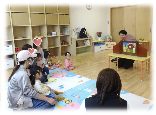 紙芝居を聞く園児と保護者の写真