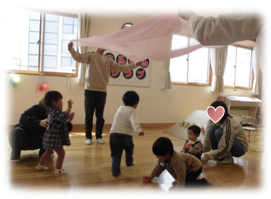 桜色のシフォンのトンネルをくぐる園児たちの写真