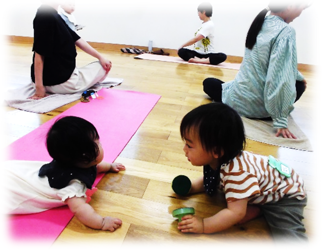 保護者の後ろで遊ぶ園児たちの写真