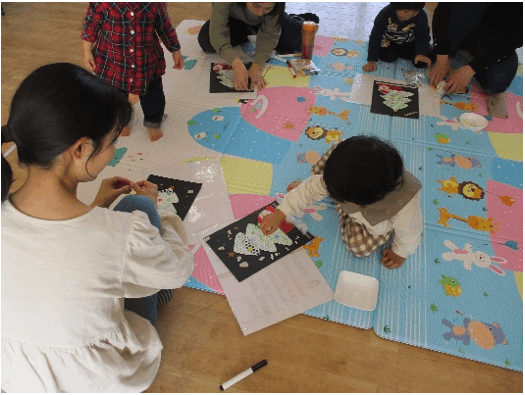 画用紙でクリスマスツリーを作る子供たち