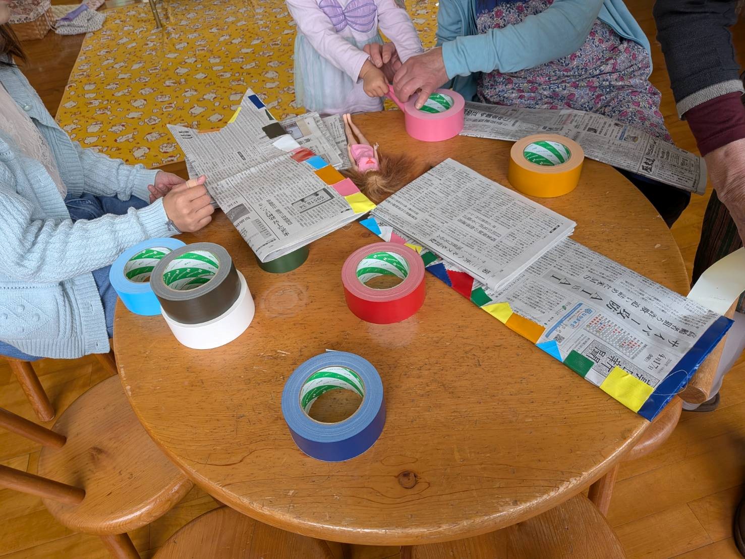 新聞紙に色とりどりのガムテープを貼っている子どもたち