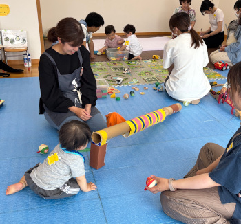 長い段ボールのパイプをのぞき込む子ども