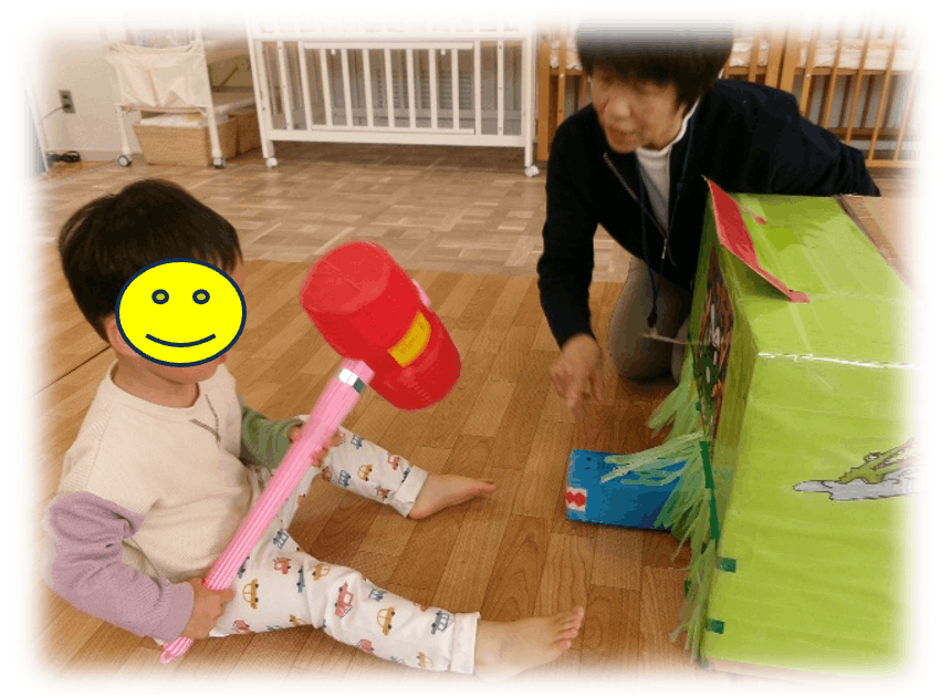 ピコピコハンマーで手作りのモグラたたきをたたく園児の写真