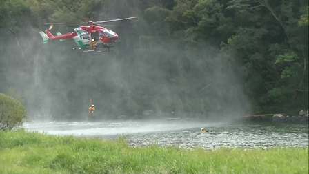 ヘリコプターと航空隊員が川に流されている要救助者を救出しようとする様子
