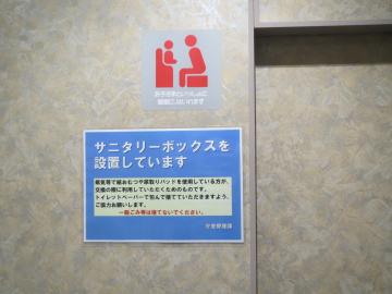 男性用個室トイレの入り口にサニタリーボックスが設置されていることについて貼紙が表示されている写真