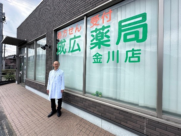 成広薬局の店舗の前で写真