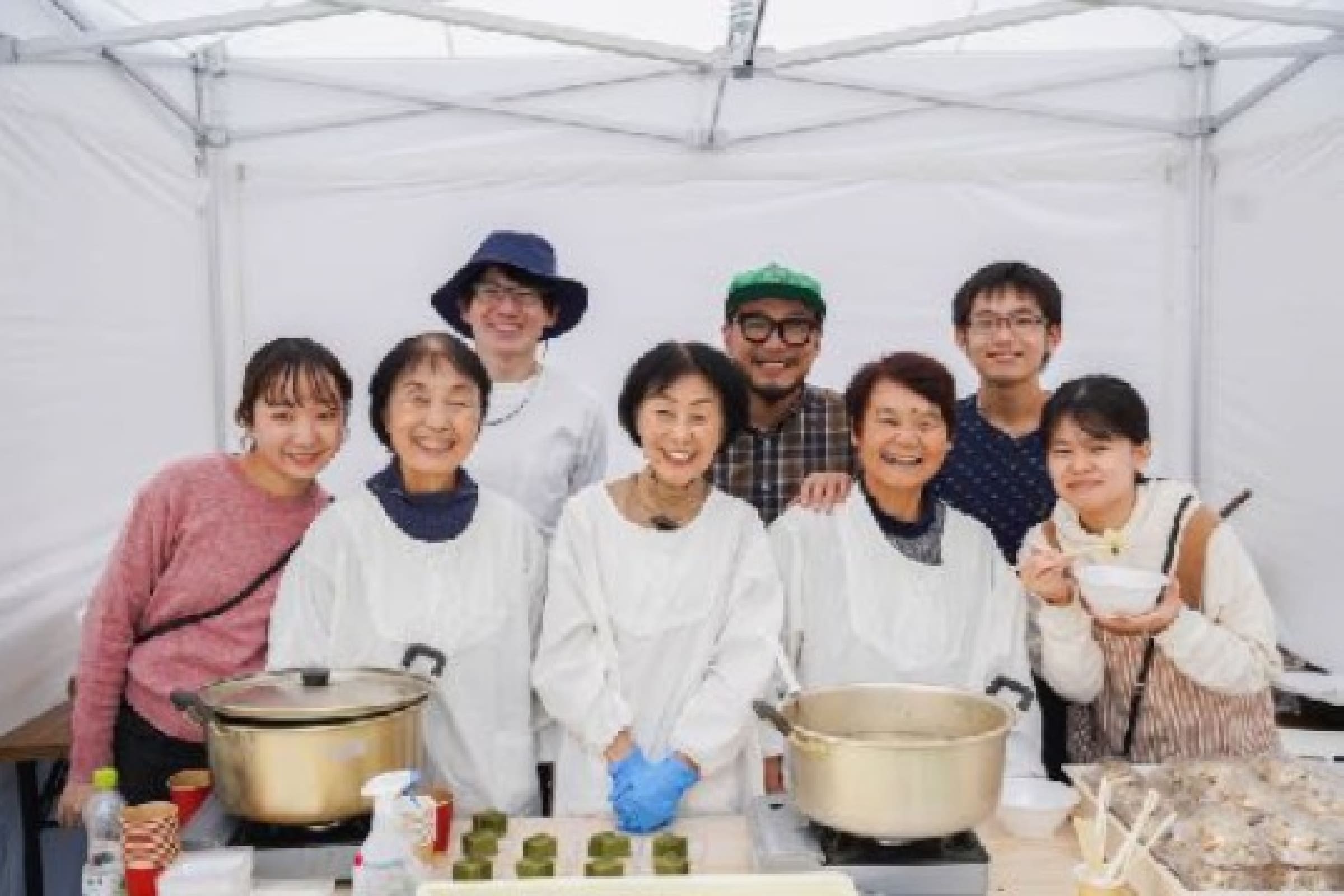 老若男女が鍋の後ろで笑っている写真