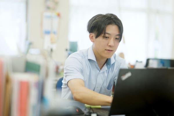 パソコンの前にいる先生の写真