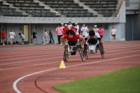 車椅子でトラック競技をする選手の写真